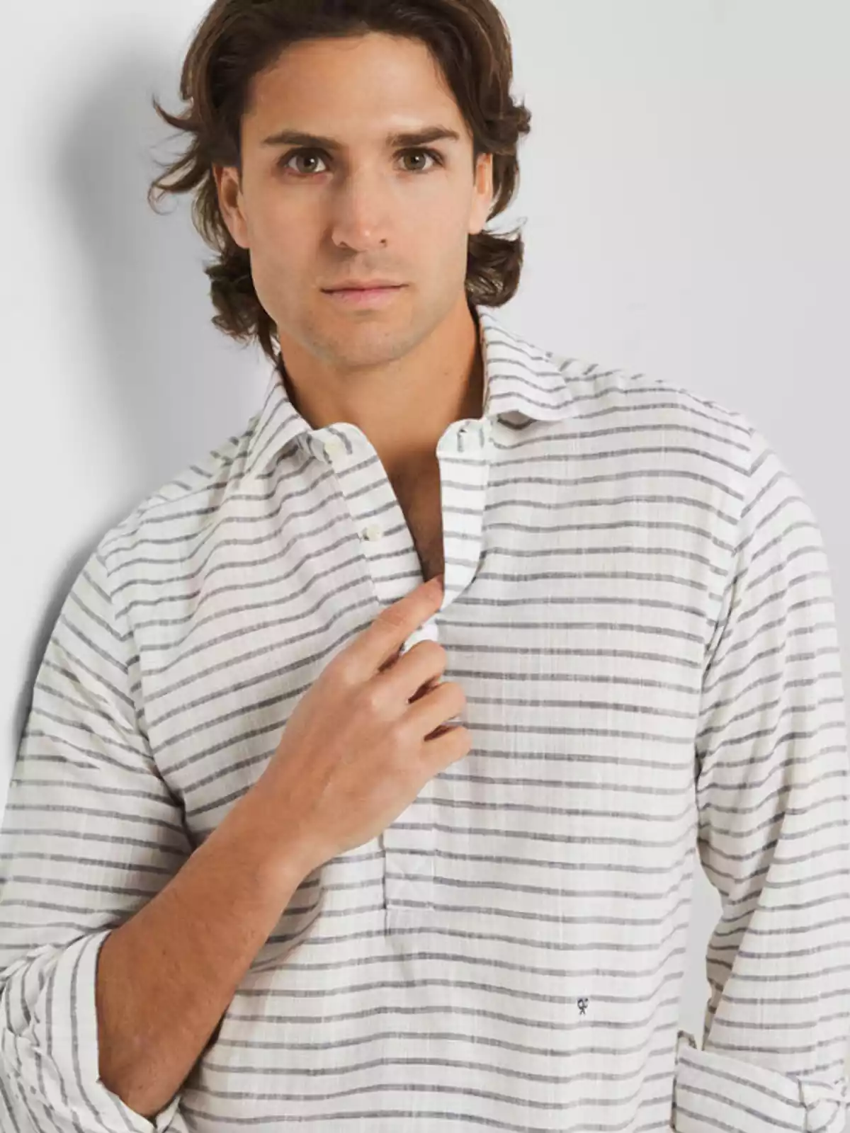 Hombre luciendo una polera de color crudo y rayas grises Hombre luciendo una polera de color crudo y rayas grises