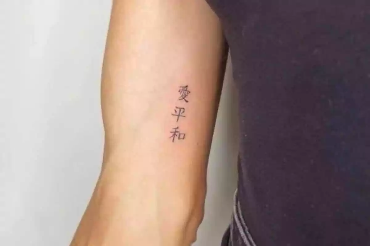 Foto detalle de un brazo que muestra un pequeño tatuaje de letras chinas Foto detalle de un brazo que muestra un pequeño tatuaje de letras chinas