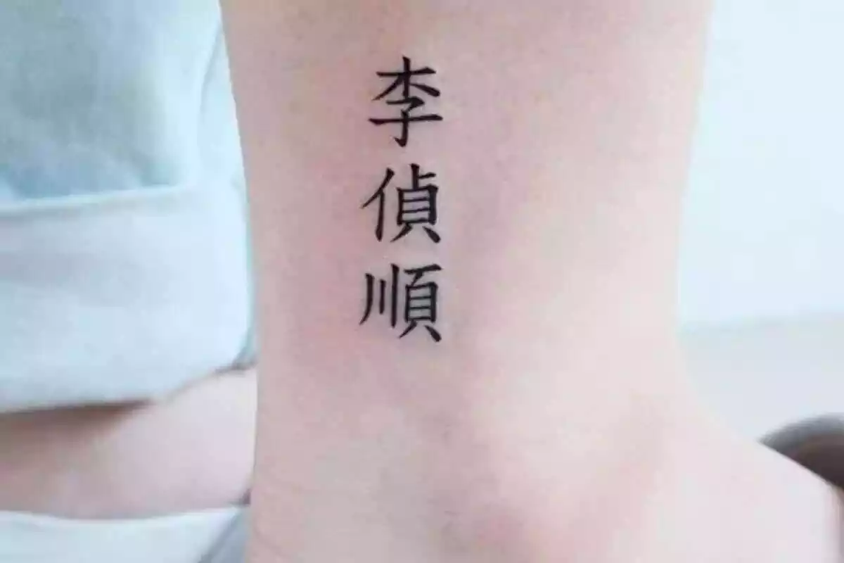 Foto detalle de una pierna con un tatuaje de letras chinas en tinta negra Foto detalle de una pierna con un tatuaje de letras chinas en tinta negra