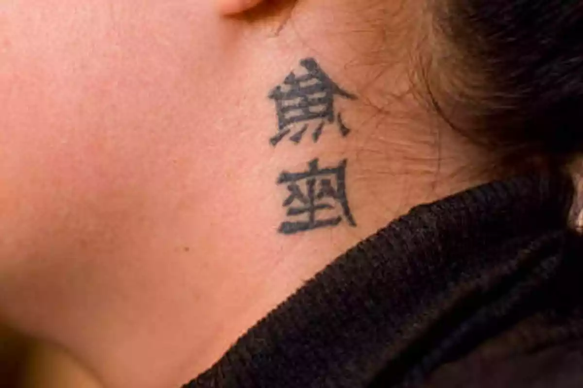 Foto detalle del cuello de una mujer que lleva un tatuaje de letras chinas Foto detalle del cuello de una mujer que lleva un tatuaje de letras chinas