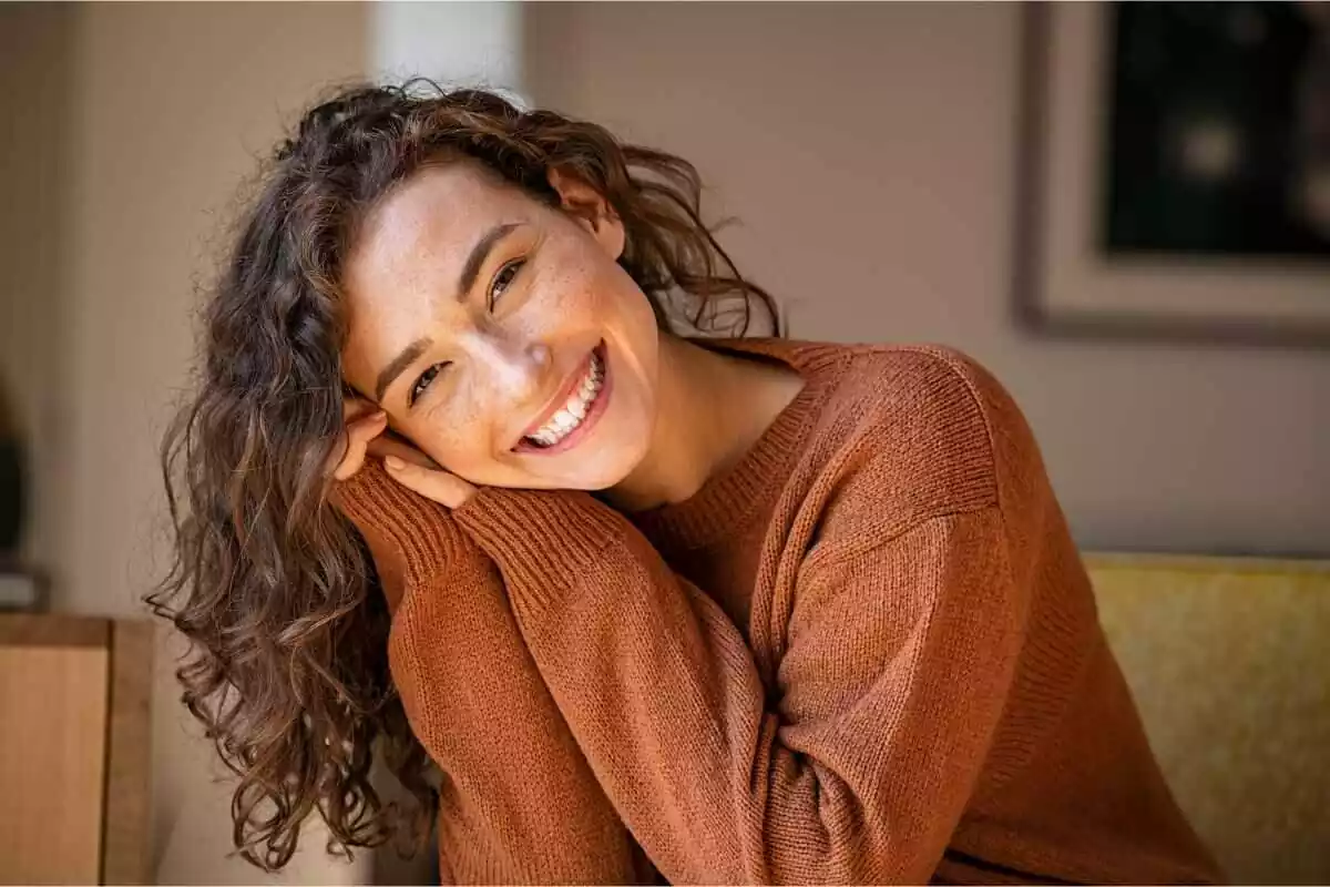 mujer sonriente con jersey color marrón