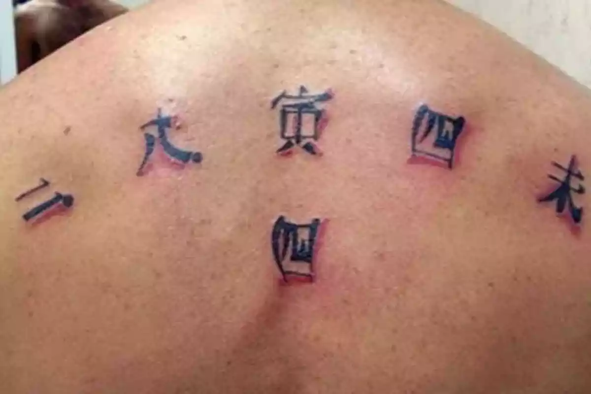 Foto detalle de una espalda masculina con un tatuaje de letras chinas Foto detalle de una espalda masculina con un tatuaje de letras chinas