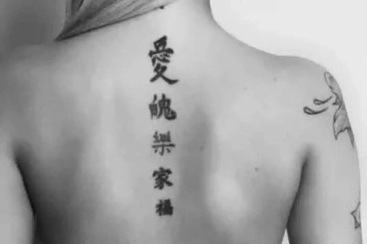 Foto detalle de una espalda femenina con un largo tatuaje de letras chinas en vertical Foto detalle de una espalda femenina con un largo tatuaje de letras chinas en vertical
