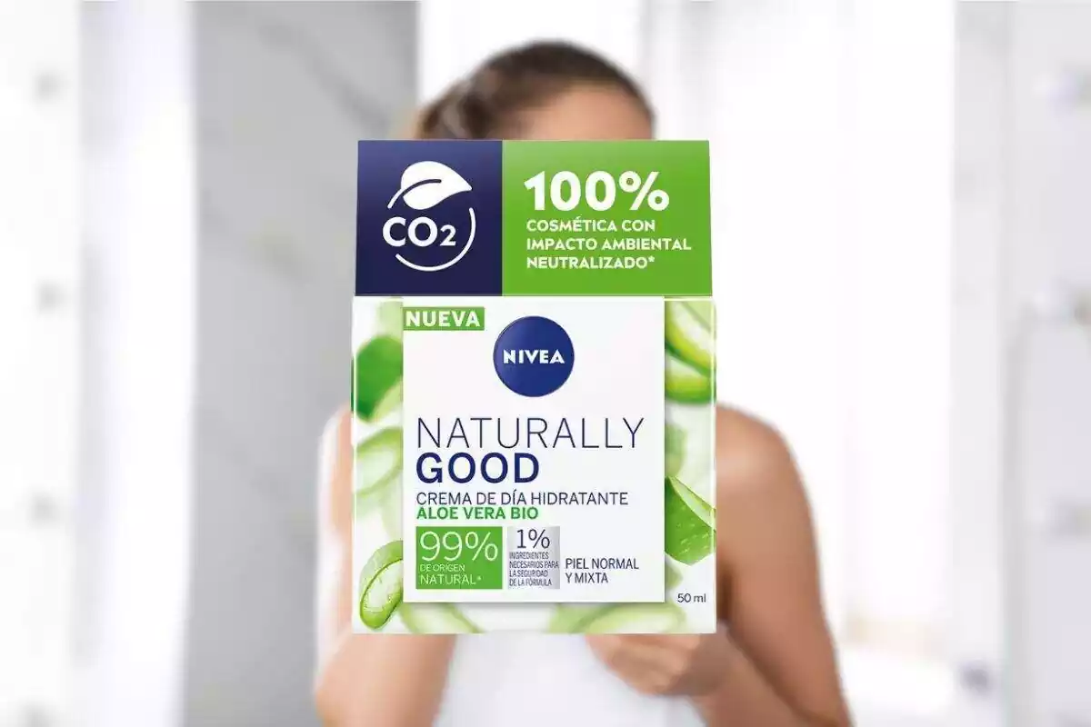 Foto de un bote de crema Naturally Good de Nivea y de fondo, desenfocada la imagen de una mujer pero está tapada por la crema Foto de un bote de crema Naturally Good de Nivea y de fondo, desenfocada la imagen de una mujer pero está tapada por la crema