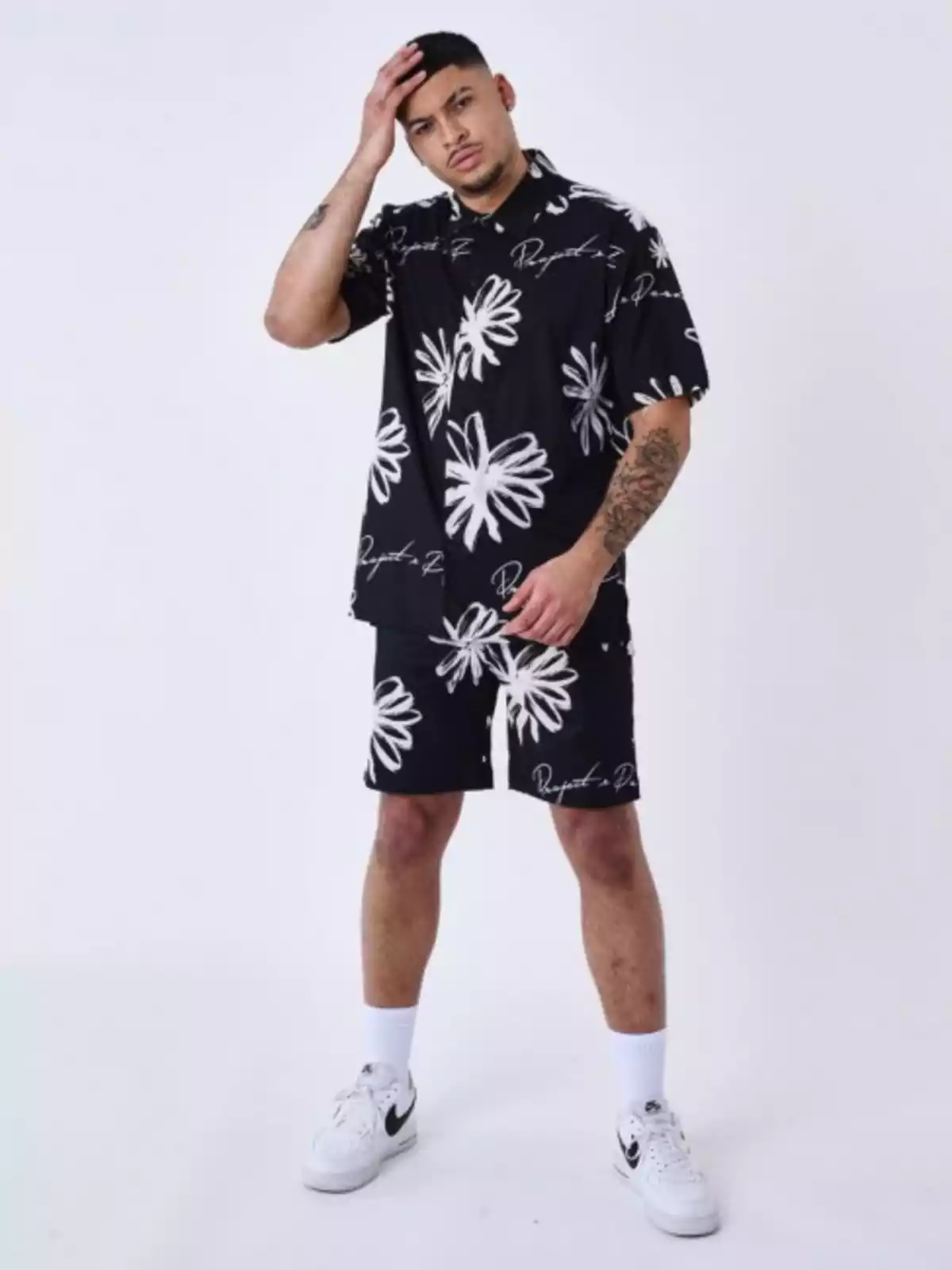 Hombre con un traje de camiseta y pantalón corto, de fondo negro y flores blancas Hombre con un traje de camiseta y pantalón corto, de fondo negro y flores blancas