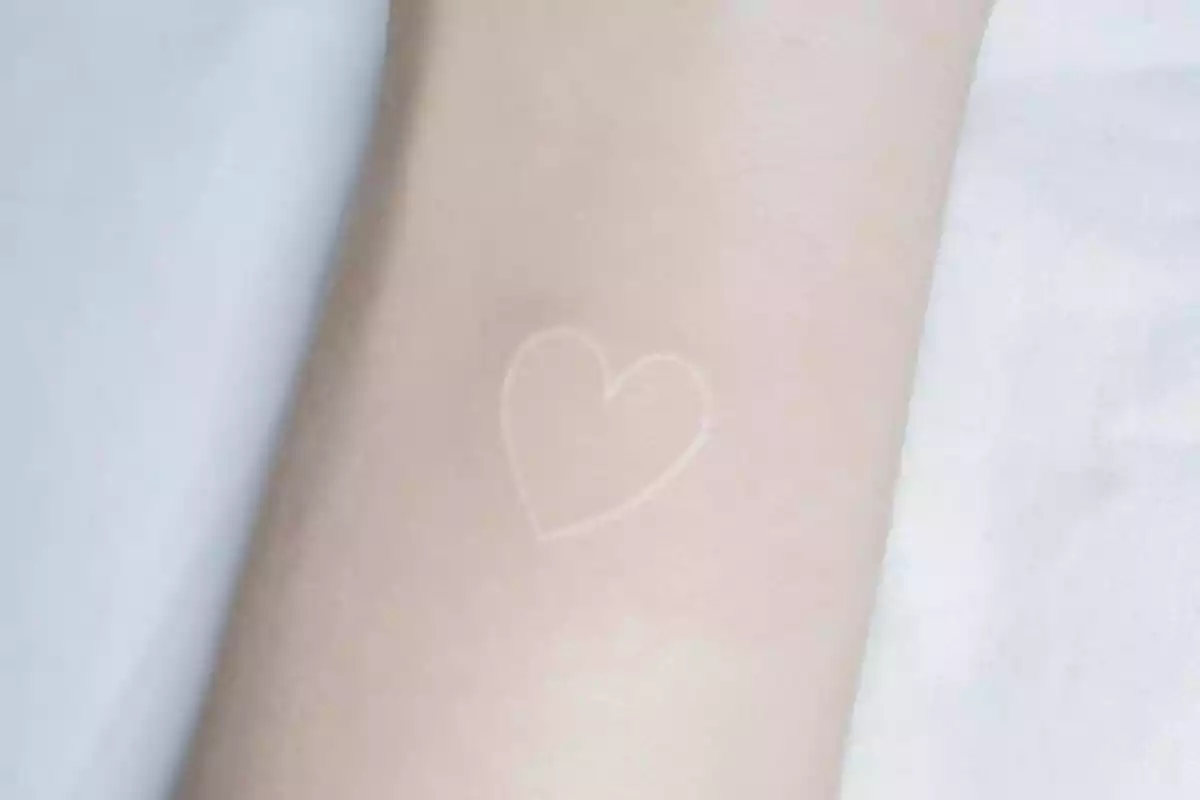 Tatuaje en el antebrazo de un corazón hecho con tinta blanca