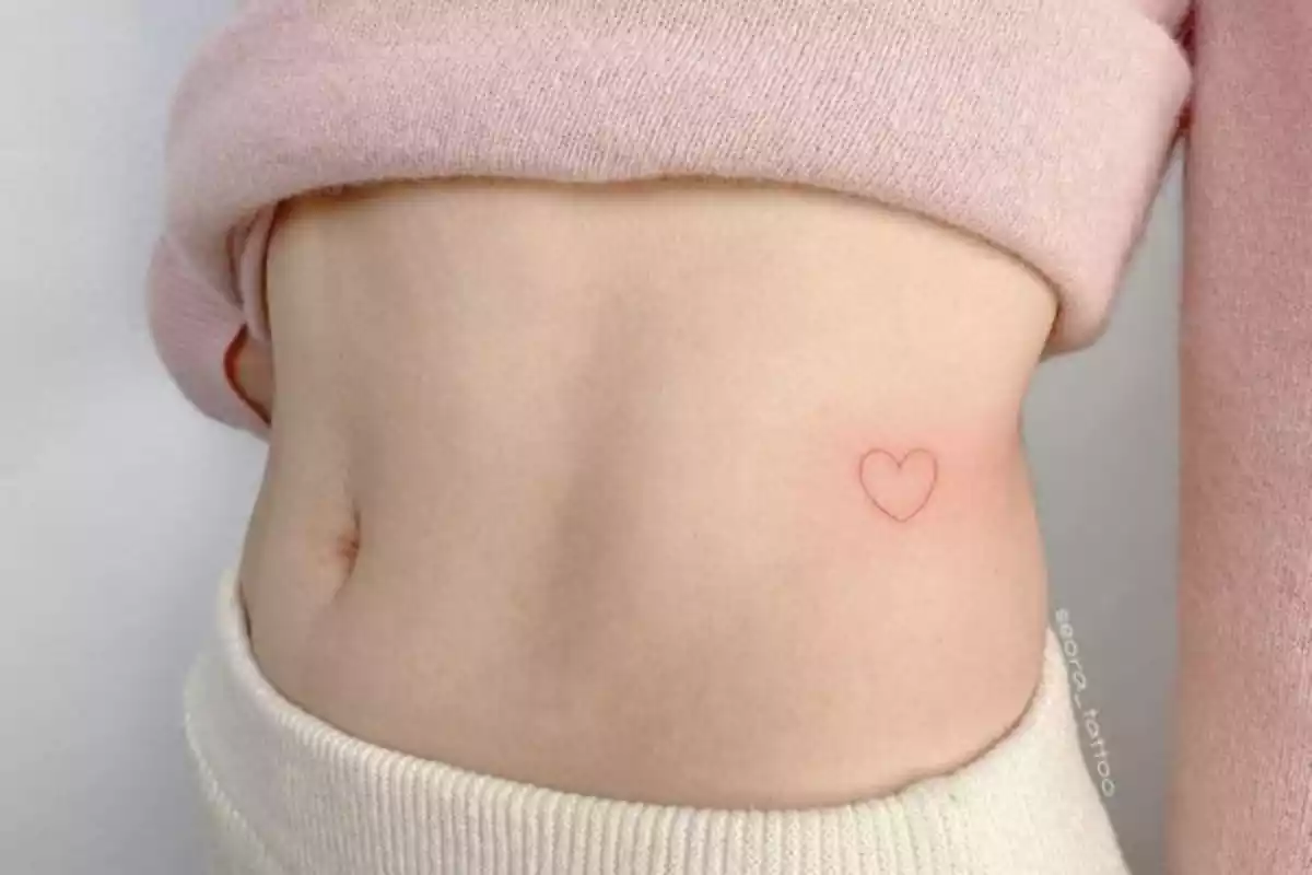 tatuaje de un corazón rojo en el costado
