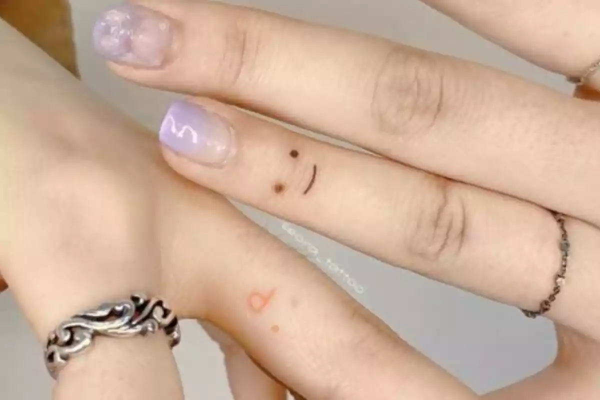 Tatuaje de cara sonriente en los dedos