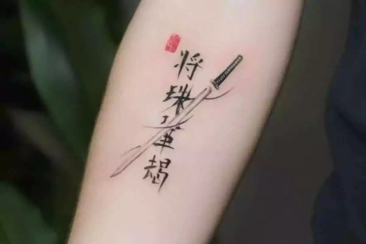 Foto detalle de un tatuaje en un brazo con letras chinas, una espalda y un símbolo en rojo Foto detalle de un tatuaje en un brazo con letras chinas, una espalda y un símbolo en rojo