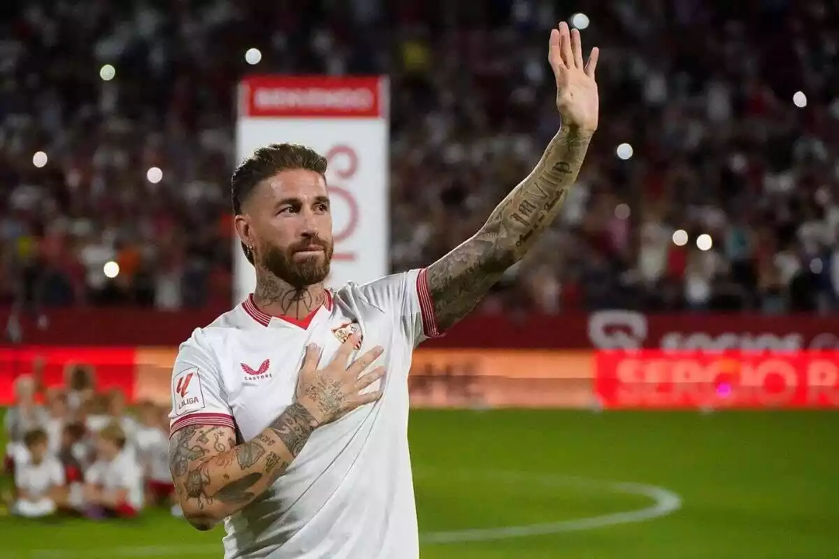 Foto del jugador Sergio Ramos con la camiseta del Sevilla, saludando a la afición emocionado con una mano levantada y la otra en el pecho