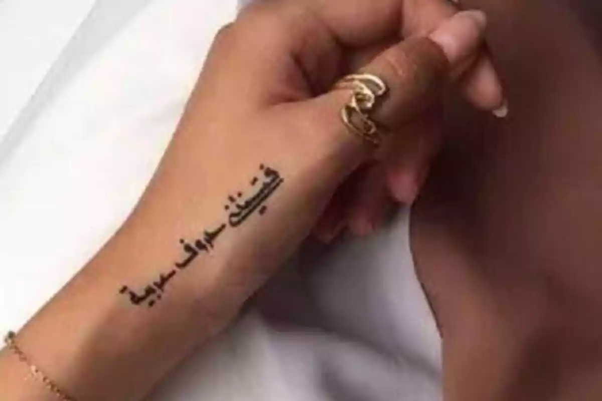 Foto de la mano de una mujer que luce un tatuaje con letras árabes Foto de la mano de una mujer que luce un tatuaje con letras árabes