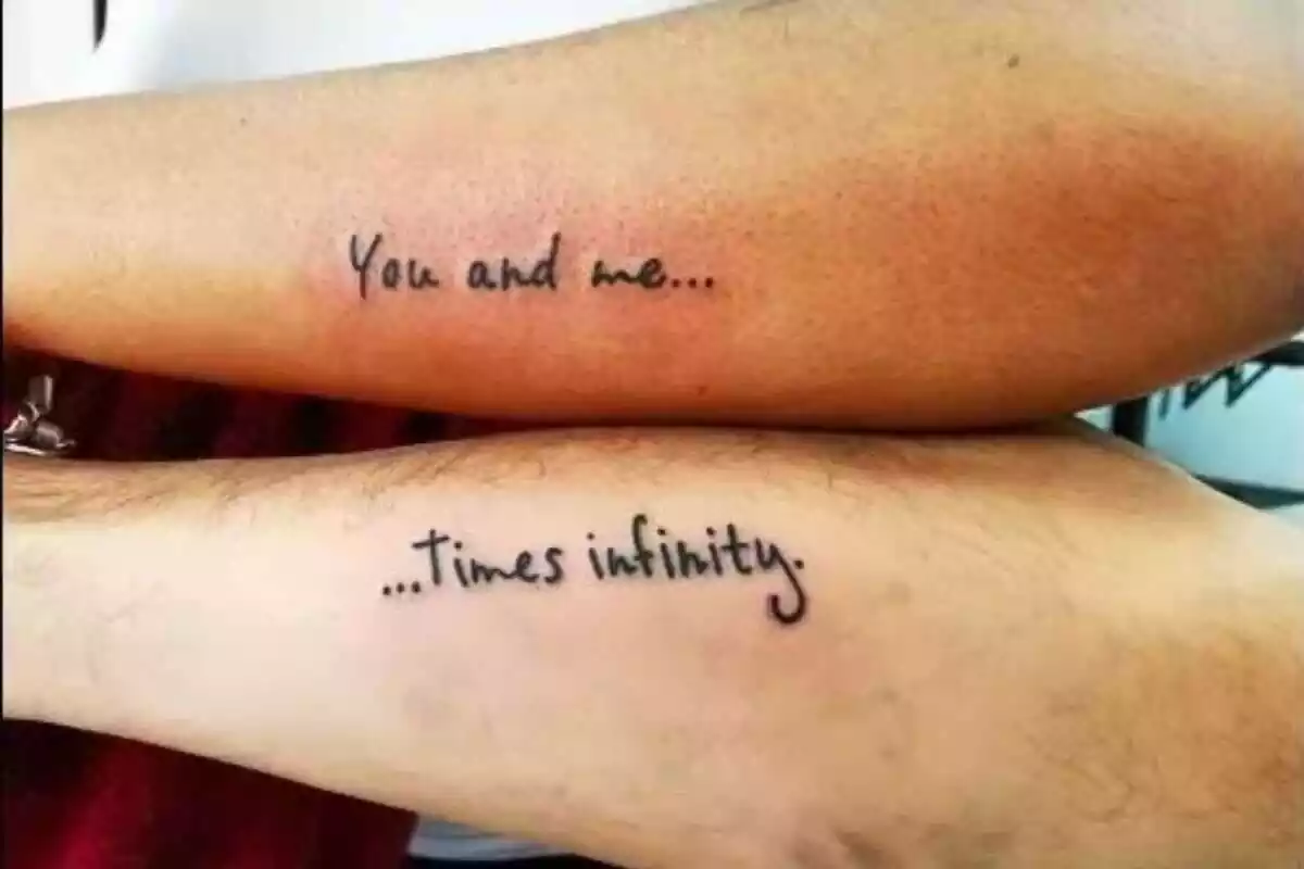Foto detalle de dos brazos que comparten tatuaje de la frase en inglés Foto detalle de dos brazos que comparten tatuaje de la frase en inglés