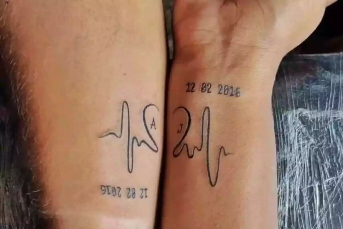 Foto detalle de unos brazos compartiendo tatuaje que forma un corazón y con una fecha de nacimiento Foto detalle de unos brazos compartiendo tatuaje que forma un corazón y con una fecha de nacimiento