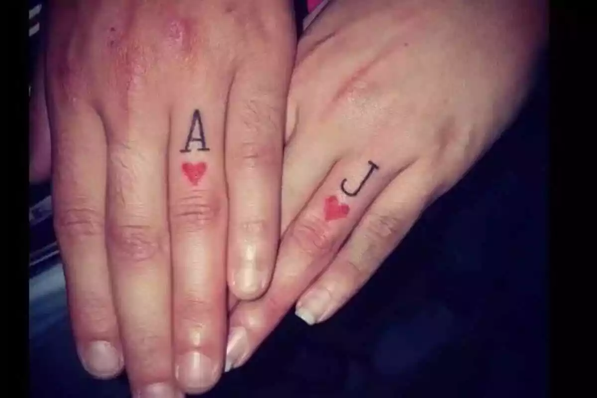 Foto detalle de la mano de un hombre y una mujer con tatuajes de sus iniciales y un corazón rojo Foto detalle de la mano de un hombre y una mujer con tatuajes de sus iniciales y un corazón rojo
