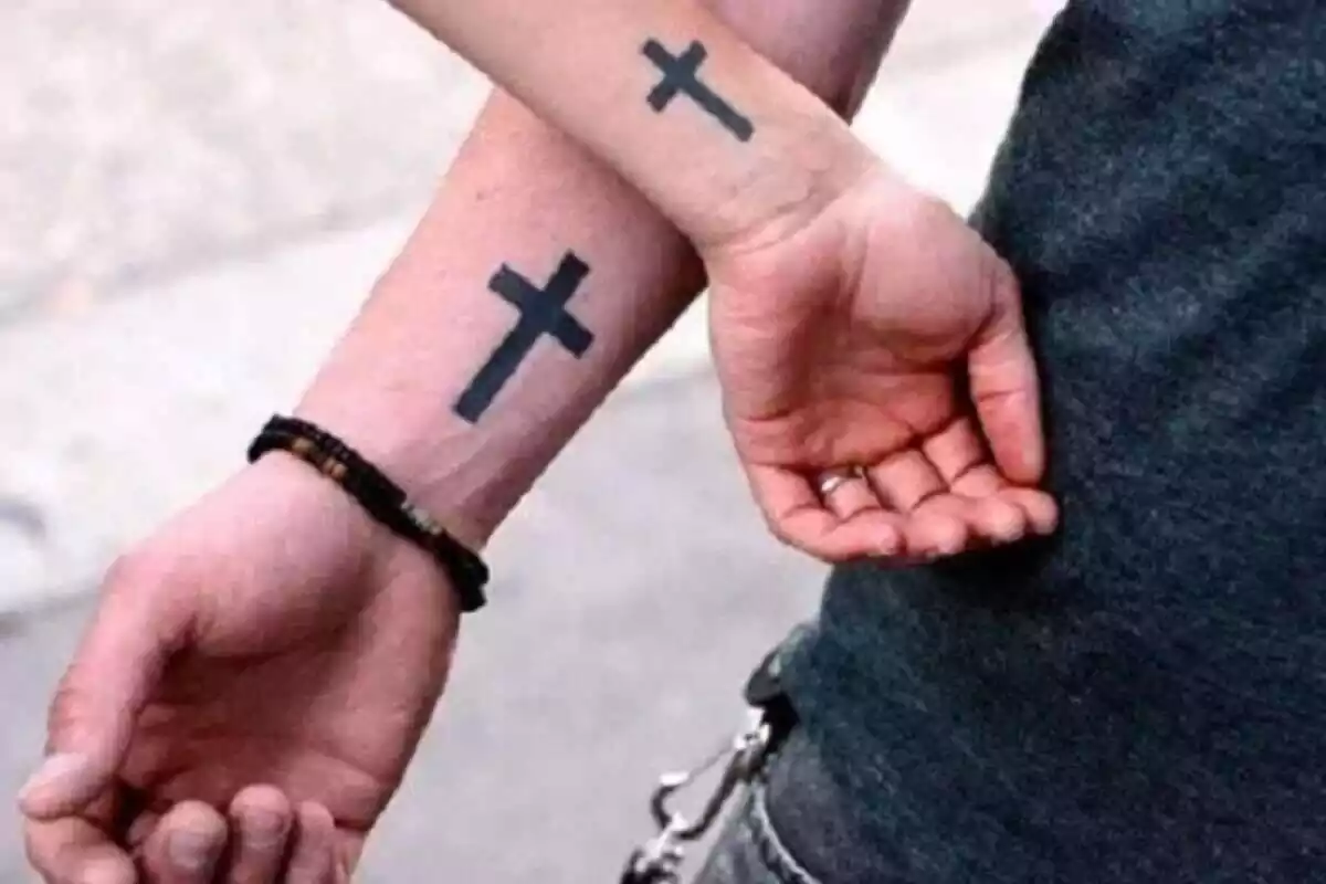 Foto detalle de unos brazos compartiendo tatuajes de cruces Foto detalle de unos brazos compartiendo tatuajes de cruces