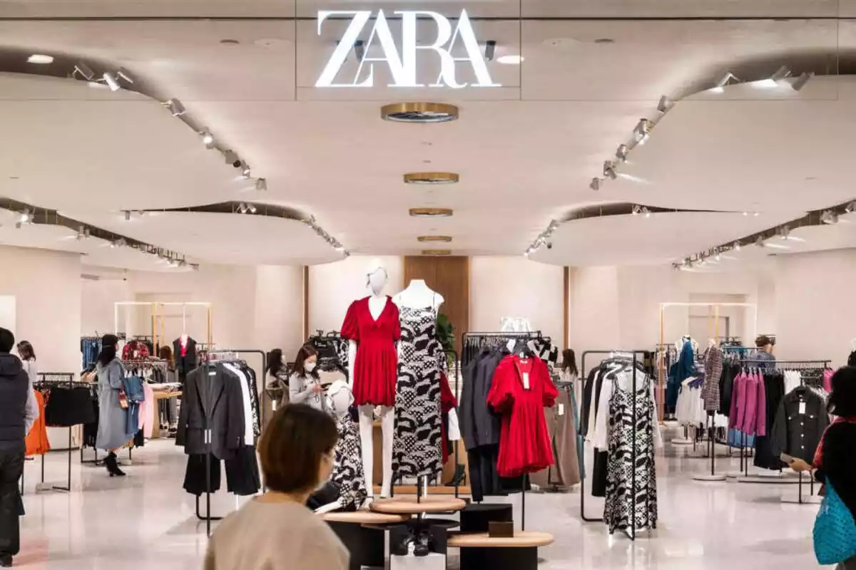 Interior de una tienda Zara. Nombre arriba y ropa colgada de distintos colores Interior de una tienda Zara. Nombre arriba y ropa colgada de distintos colores