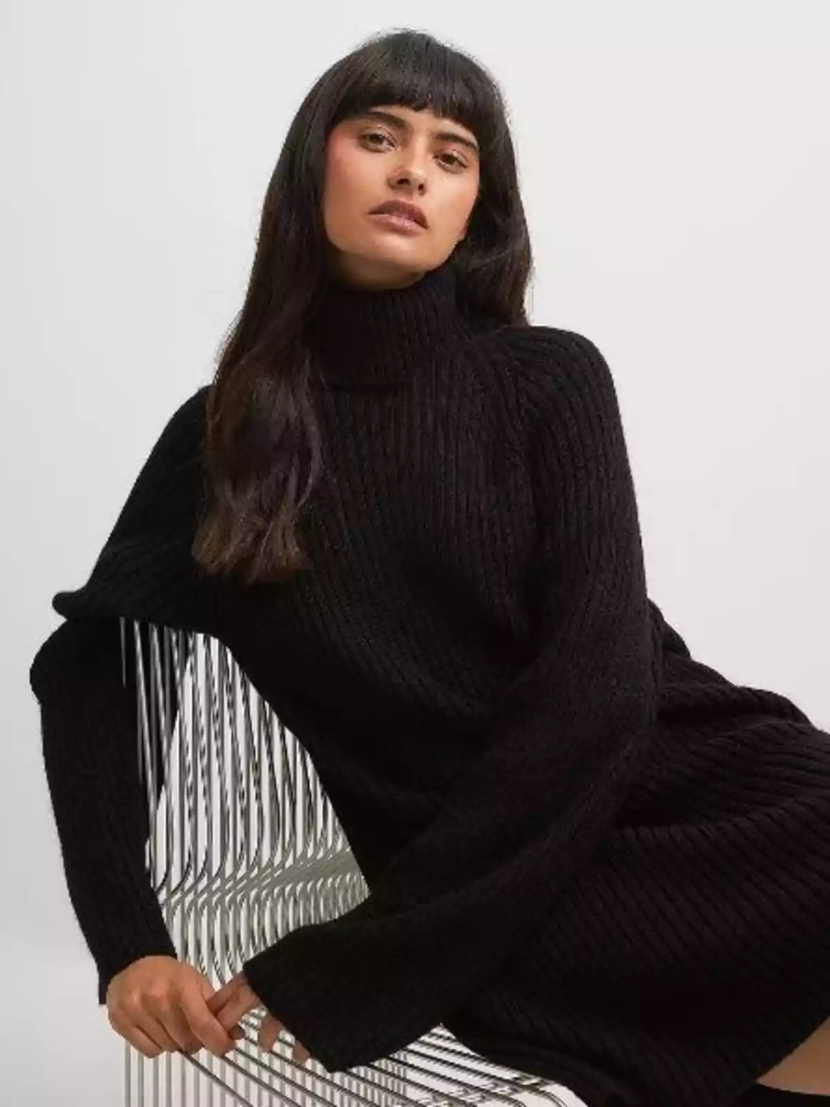 Mujer lleva un vestido maxi de punto de color negro y de cuello alto Mujer lleva un vestido maxi de punto de color negro y de cuello alto
